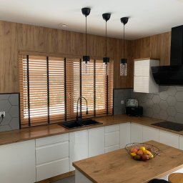 Palk-Art Design - Kuchnia z drewnianymi żaluzjami poziomymi w oknie, czarną armaturą i heksagonalnymi płytkami. Widoczne trzy lampy wiszące i drewniane blaty.