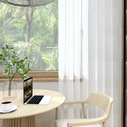 Virtual Space - Jasne wnętrze z okrągłym stołem, laptopem i filiżanką kawy. Za oknem zieleń, obok przeszklona witryna z drewnianymi elementami. Minimalistyczny styl.