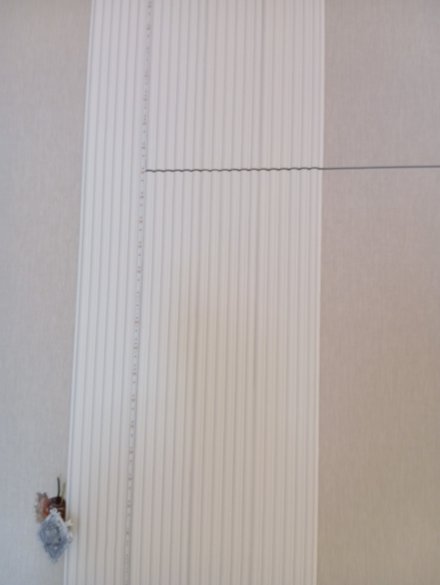 Ściana z zamontowaną listwą dekoracyjną z pionowymi żłobieniami i taśmą LED. Widoczny fragment instalacji elektrycznej.