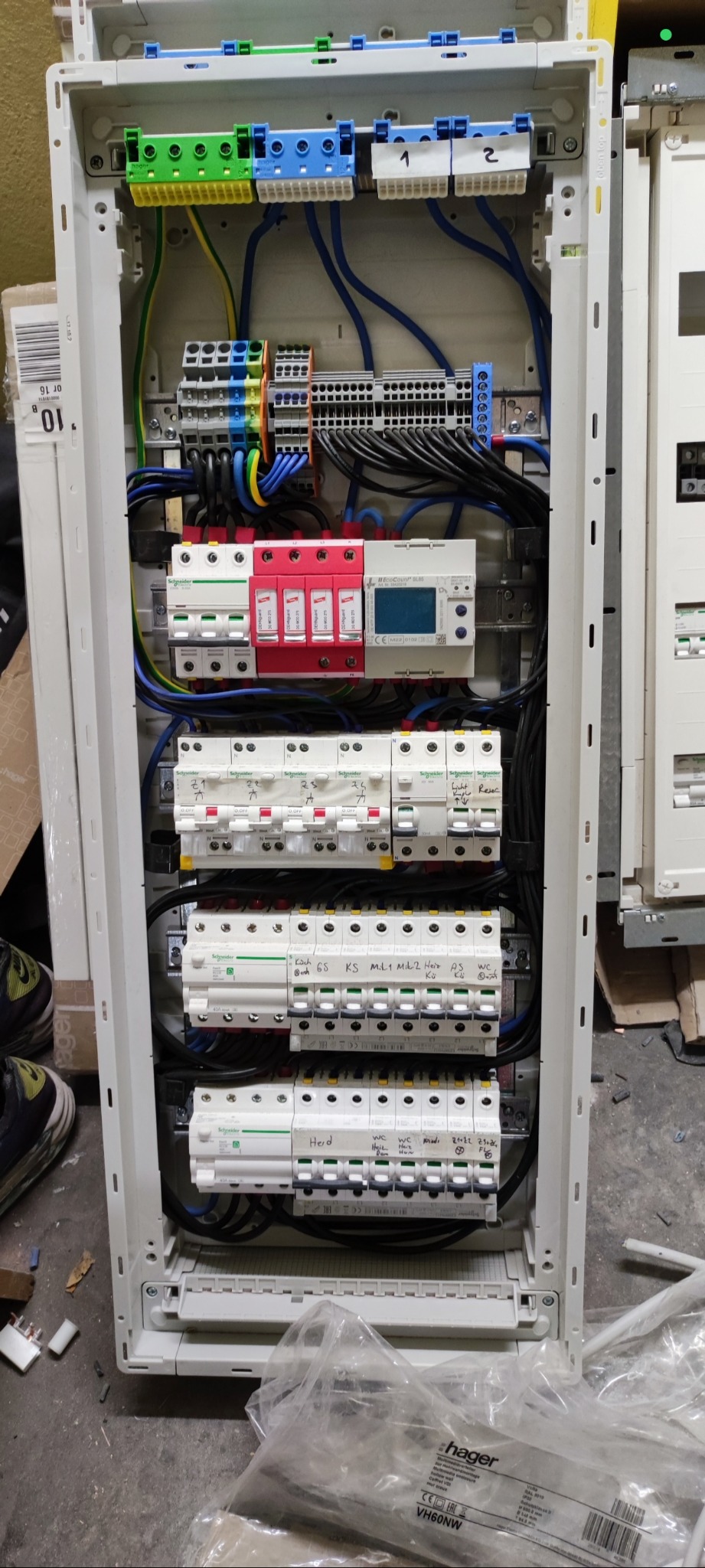 Rozdzielnica elektryczna Hager z zainstalowanymi zabezpieczeniami, bezpiecznikami i przewodami. Widoczne elementy opisane ręcznie.