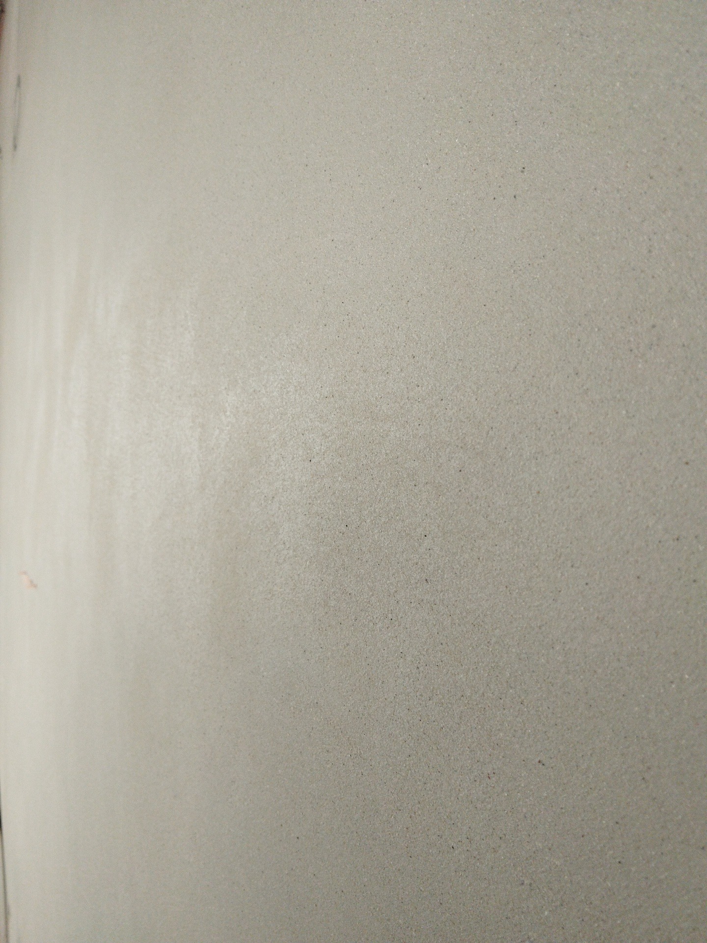 Świeżo nałożony, gładki tynk maszynowy w odcieniach szarości, z delikatną fakturą i subtelnymi smugami światła, ukazujący precyzję wykonania.