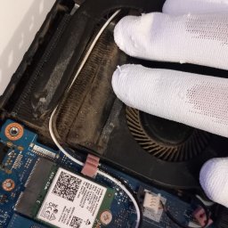 HUBICHEM Hubert Wodnicki - Wnętrze laptopa z widocznym wentylatorem chłodzącym, dyskiem SSD Western Digital 512GB i kartą sieciową, czyszczone przez osobę w białych rękawiczkach.