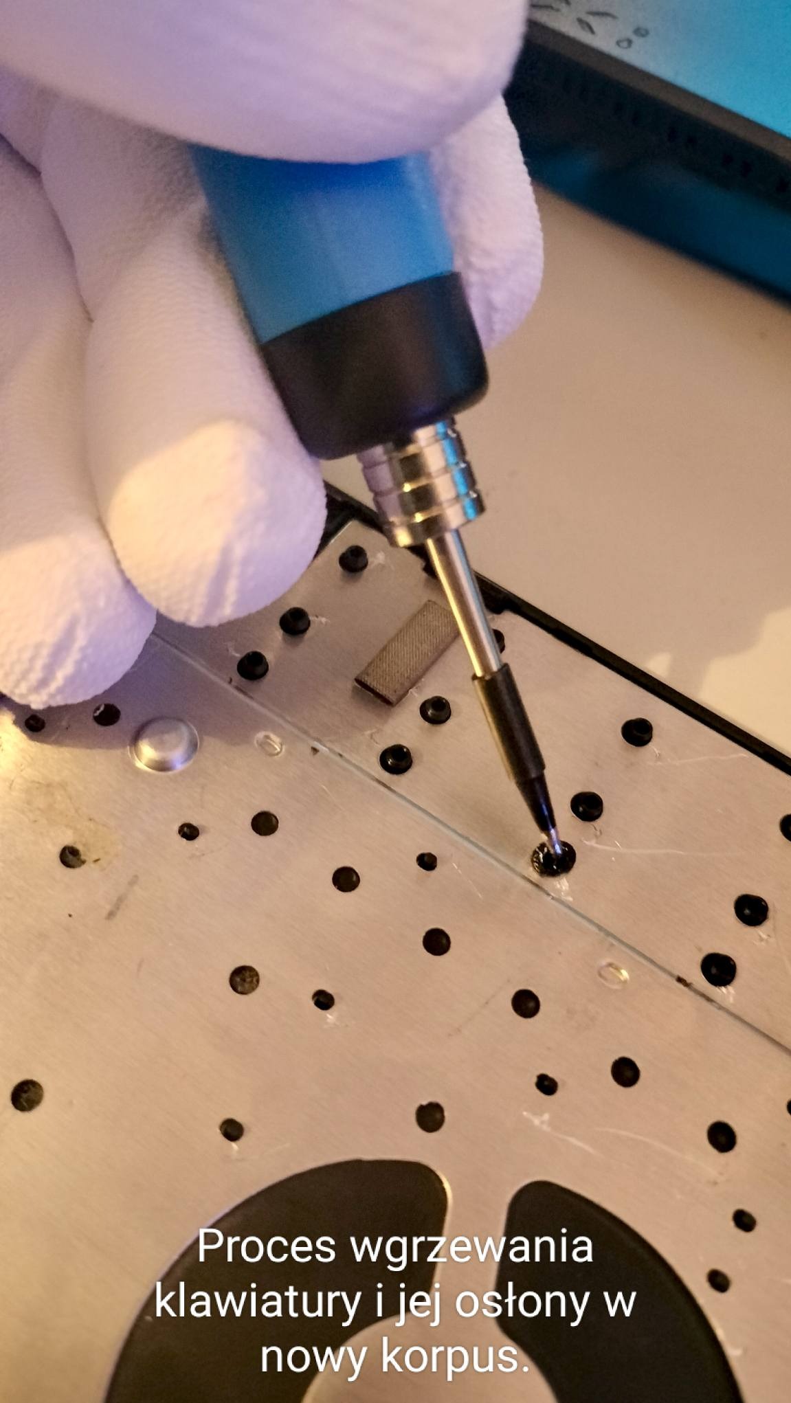 Wkręcanie śrubki w obudowę klawiatury laptopa za pomocą precyzyjnego wkrętaka, dłoń w białej rękawiczce. Detal naprawy elektroniki, bliskie ujęcie.