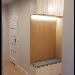 ASGARD - MAREK BIERZOŃSKI - Nowoczesny przedpokój z zabudową meblową: białe szafki, drewniana wnęka z podświetleniem LED i siedziskiem. Minimalistyczny design, jasne kolory, drewniana podłoga.