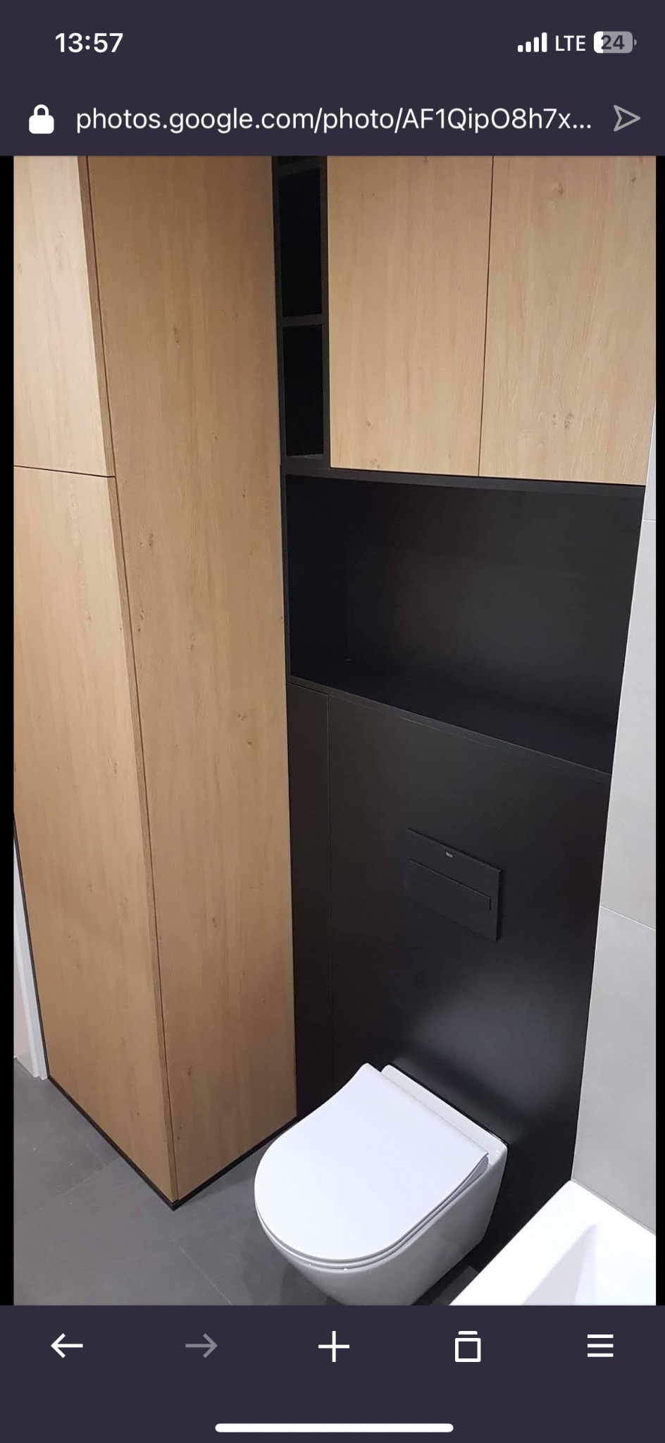 Nowoczesna łazienka z zabudową meblową w odcieniach drewna i czerni, podwieszana toaleta. Minimalistyczny design, szare płytki podłogowe.