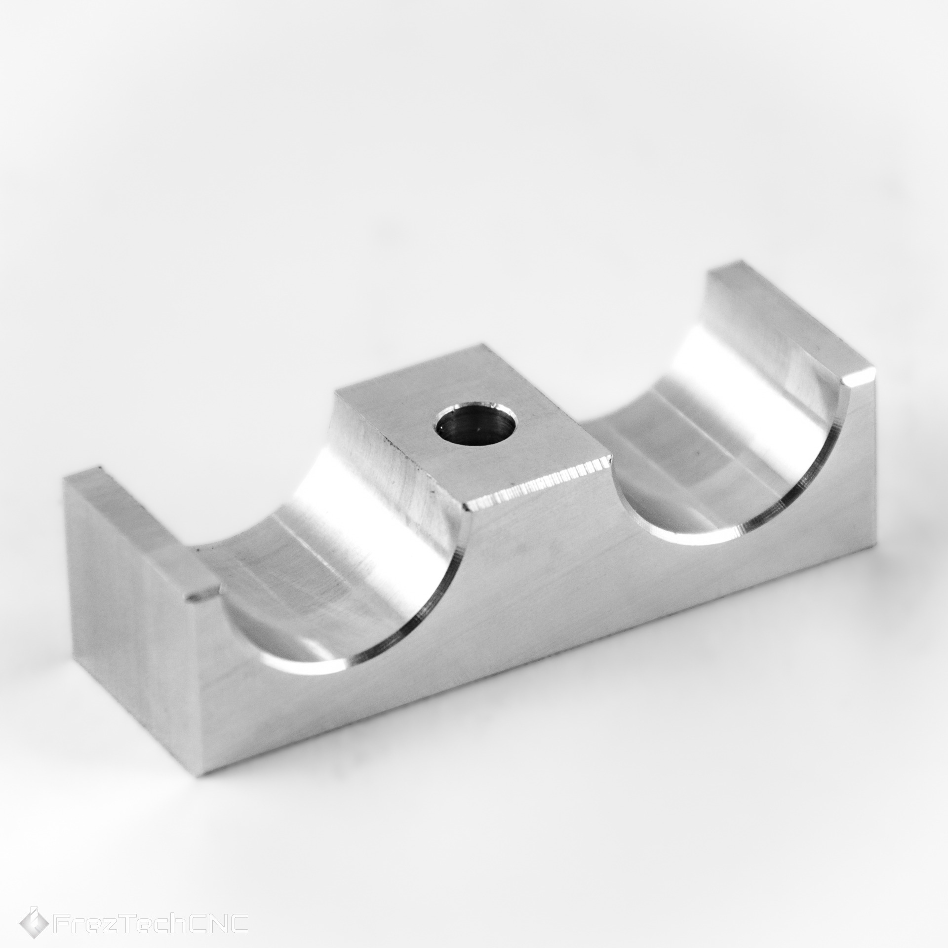 Precyzyjnie obrobiony element metalowy CNC z otworem, widoczne ślady frezowania, na jasnym tle. Detal z bliska, ukazujący dokładność wykonania.