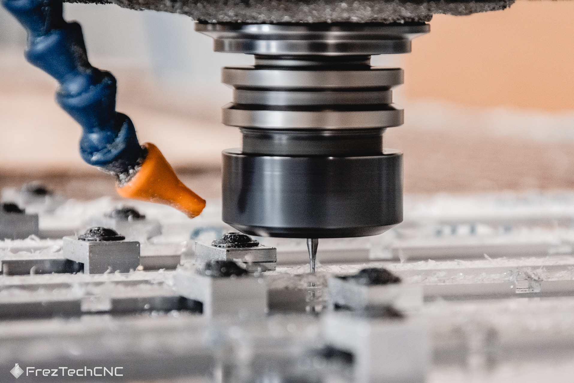 Precyzyjna praca frezarki: metalowy element obrabiany w zbliżeniu, widoczne wióry i chłodziwo. Detaliczne ujęcie procesu.