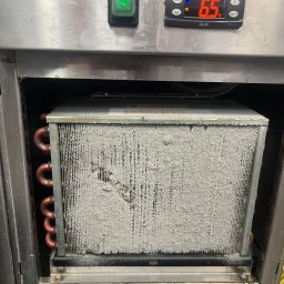 Technika Chłodnicza Jakub Mruk - Zaszroniony parownik wewnątrz urządzenia chłodniczego, widoczne miedziane rurki i wyświetlacz temperatury wskazujący 6.5°C. Urządzenie w obudowie ze stali nierdzewnej.