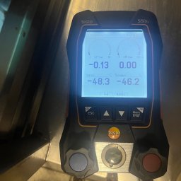 Technika Chłodnicza Jakub Mruk - Miernik cyfrowy Testo 550s z podłączonymi przewodami, wyświetlający parametry chłodnicze, takie jak ciśnienie i temperatura, na tle metalowej powierzchni.