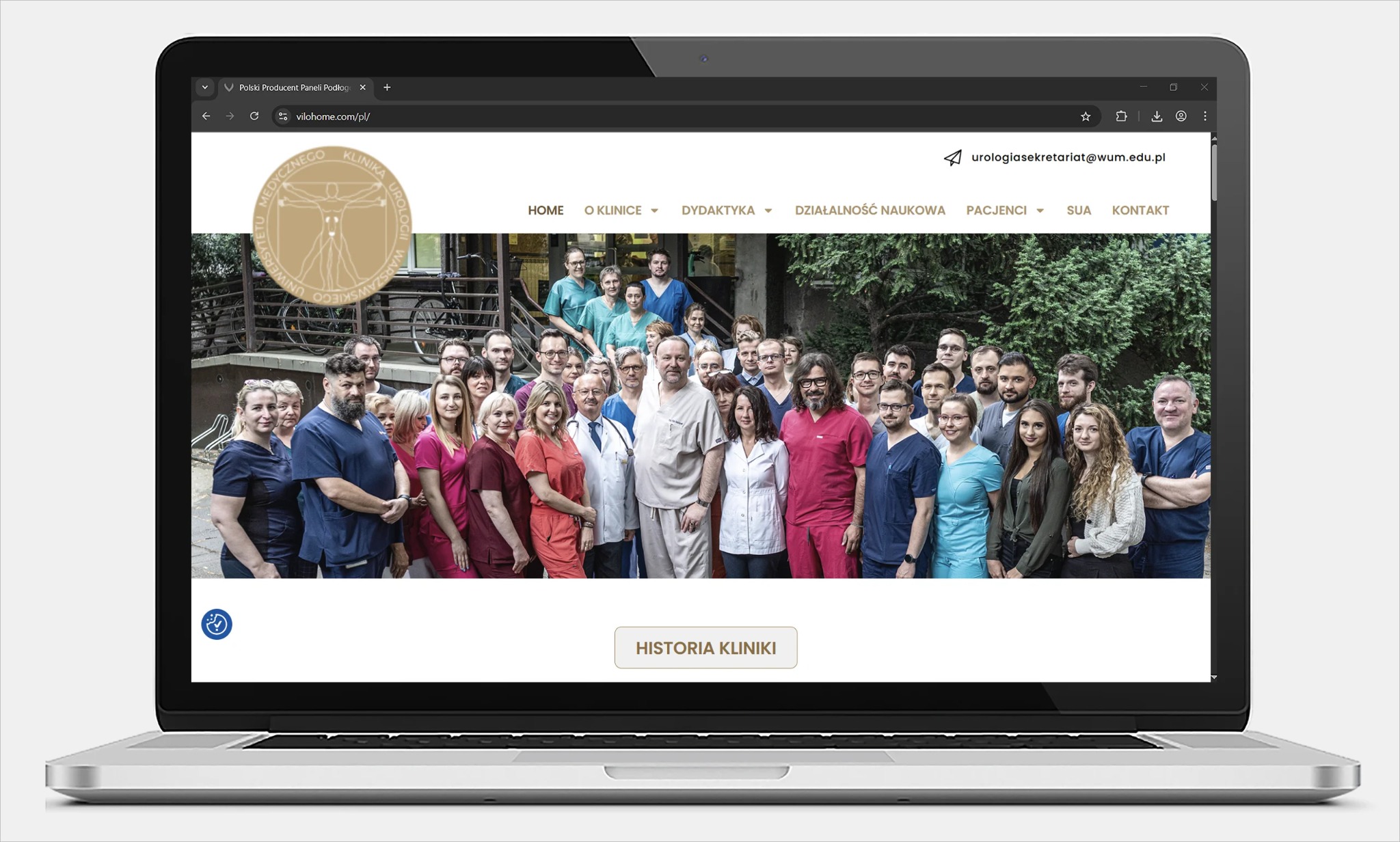 Laptop wyświetla stronę internetową kliniki urologicznej z grupowym zdjęciem personelu medycznego na tle zieleni. Widoczny adres e-mail i menu strony.