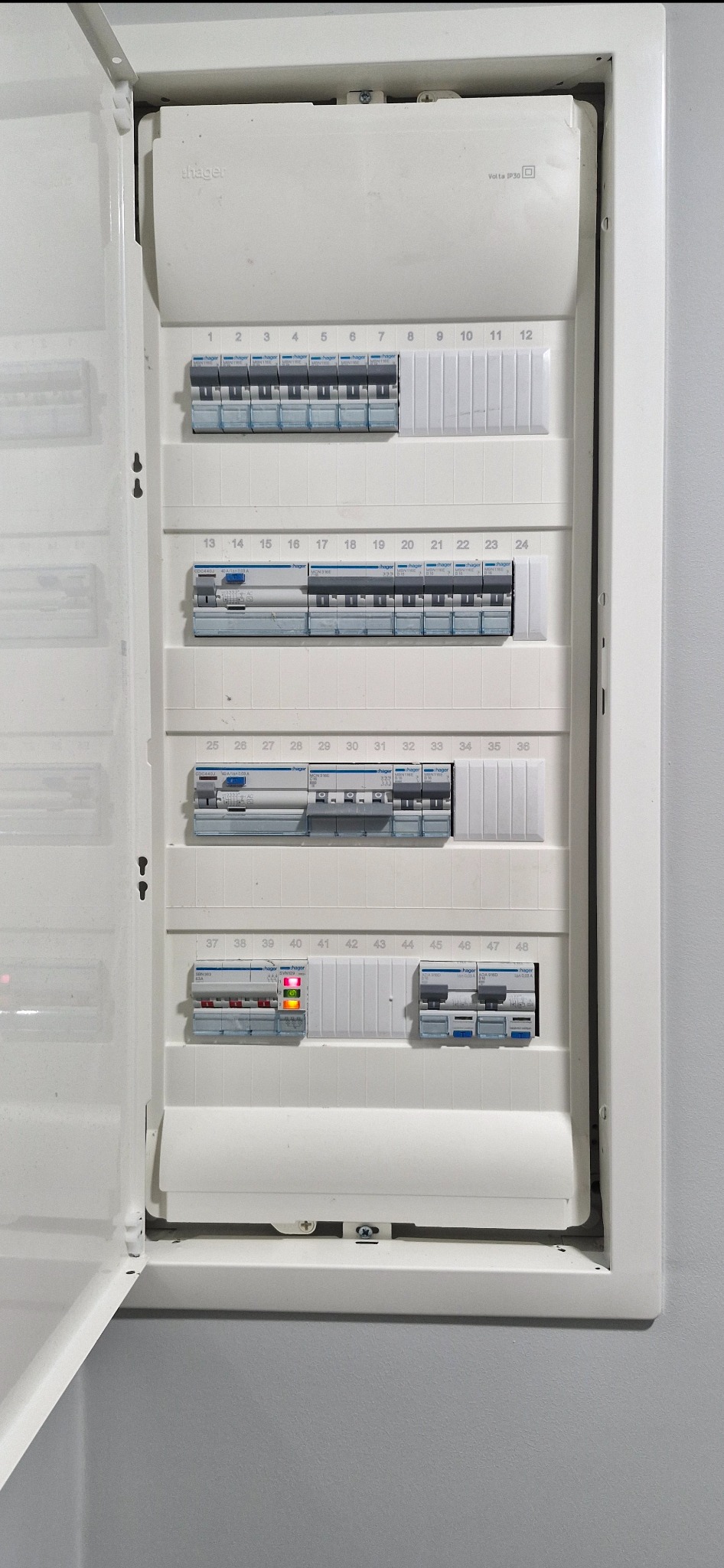 Otwarta, biała skrzynka elektryczna Hager Volta IP30 z bezpiecznikami. Jeden z bezpieczników (nr 39) w pozycji włączonej, sygnalizuje działanie diodą LED.