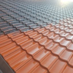 Kolor wash - Częściowo umyty dach z czerwonej dachówki, widoczna różnica między czystą a zabrudzoną powierzchnią. Blask słońca na mokrych dachówkach.