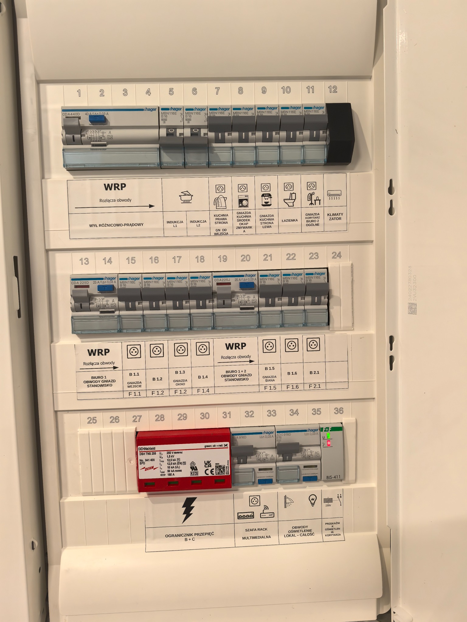 Rozdzielnica elektryczna Hager z opisami obwodów, zabezpieczeniami i wyłącznikami, widok z bliska, oświetlenie górne.