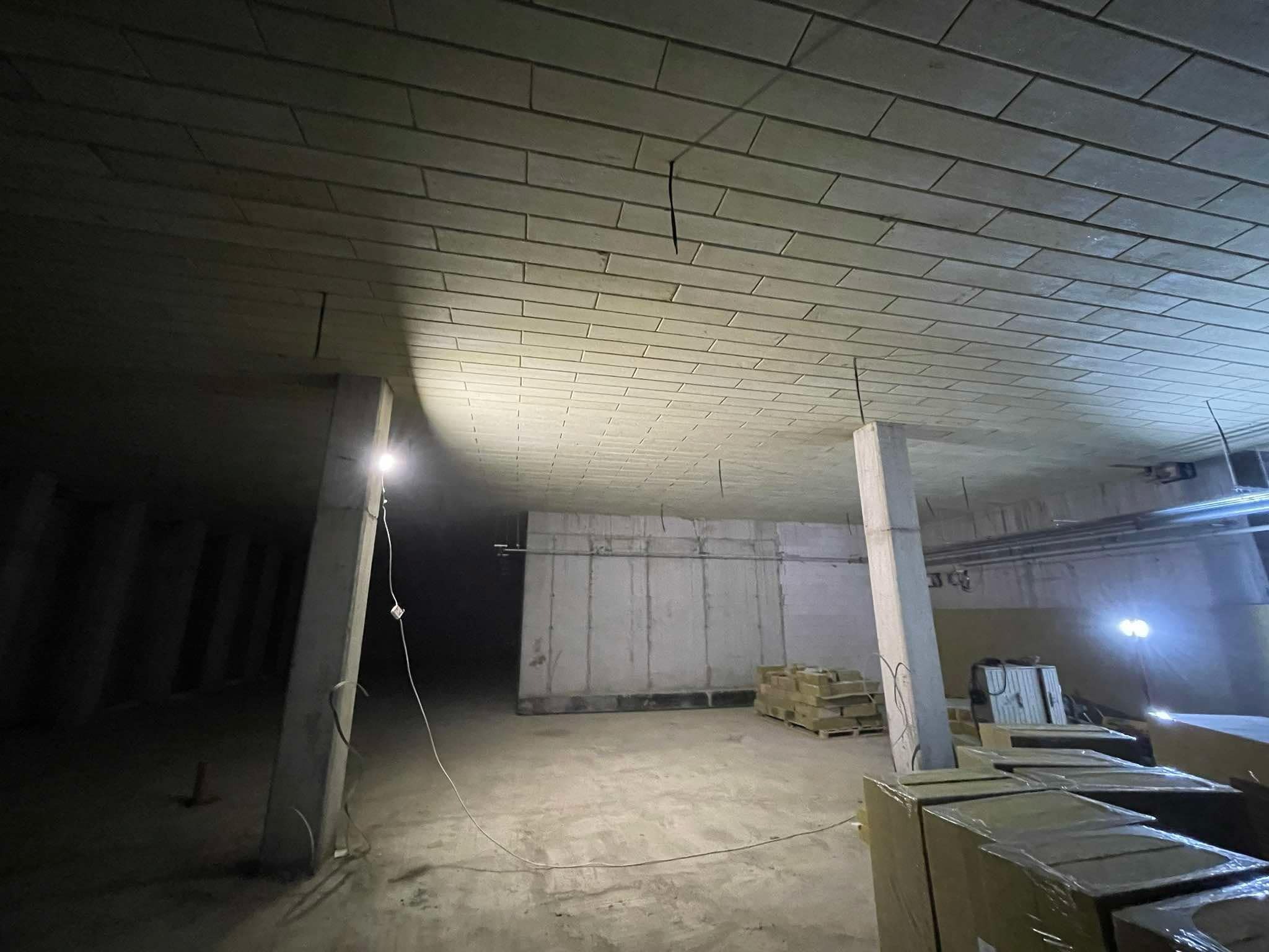 Sufit z płyt kartonowo-gipsowych w surowym wnętrzu, oświetlony punktowo, z widocznymi elementami konstrukcyjnymi i materiałami budowlanymi.