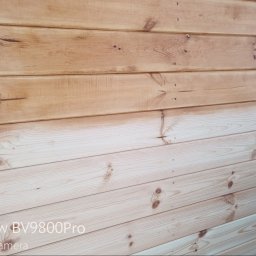 CLEAN WALL NON PROFIT SPÓŁKA Z OGRANICZONĄ ODPOWIEDZIALNOŚCIĄ - Drewniana elewacja w trakcie czyszczenia: górna część po zabiegu, dolna surowa. Widoczne sęki i gwoździe. Częściowo widoczny materiał ochronny.