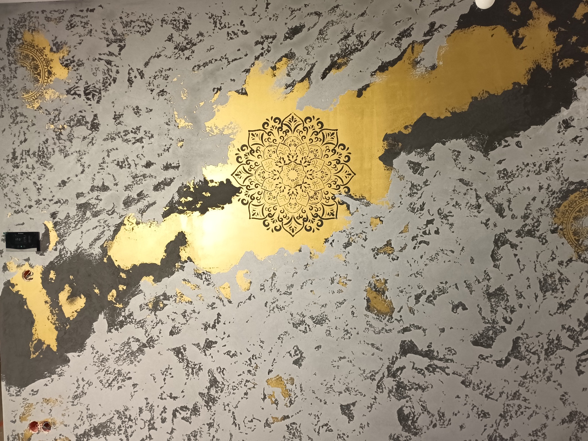 Dekoracyjna ściana z efektem betonu, złote plamy i ornament mandala. Unikalna faktura i wzór, nowoczesny design wnętrza z elementami artystycznymi.