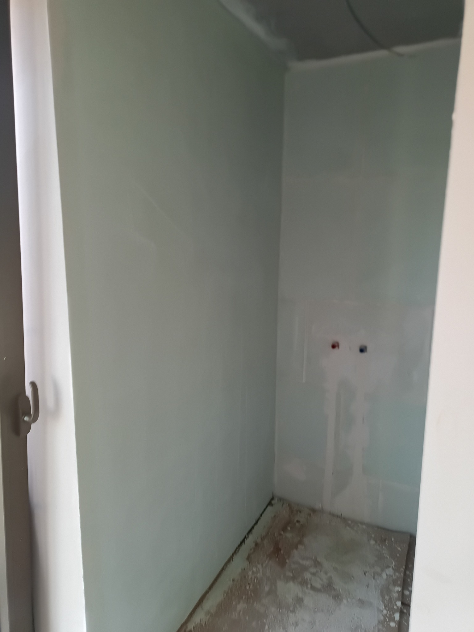 Wnętrze łazienki w trakcie wykańczania w Turku. Widoczne ściany przygotowane pod płytki, z wyprowadzonymi instalacjami wodnymi. Podłoga wymaga dalszych prac.