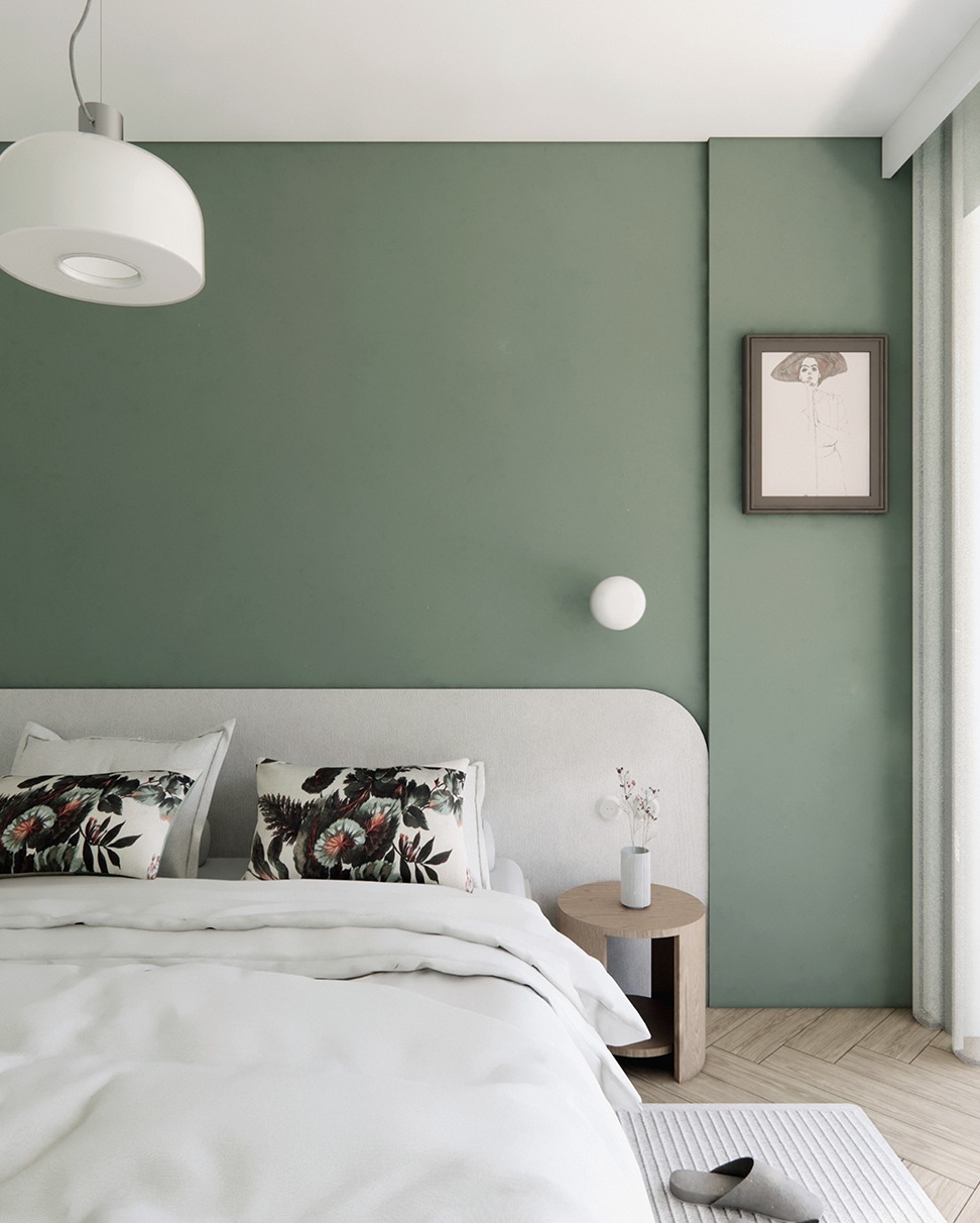 Nowoczesna sypialnia w odcieniach zieleni z łóżkiem z białym nakryciem, wzorzystymi poduszkami i okrągłą lampą. Na ścianie obraz w ramie i mała lampka.