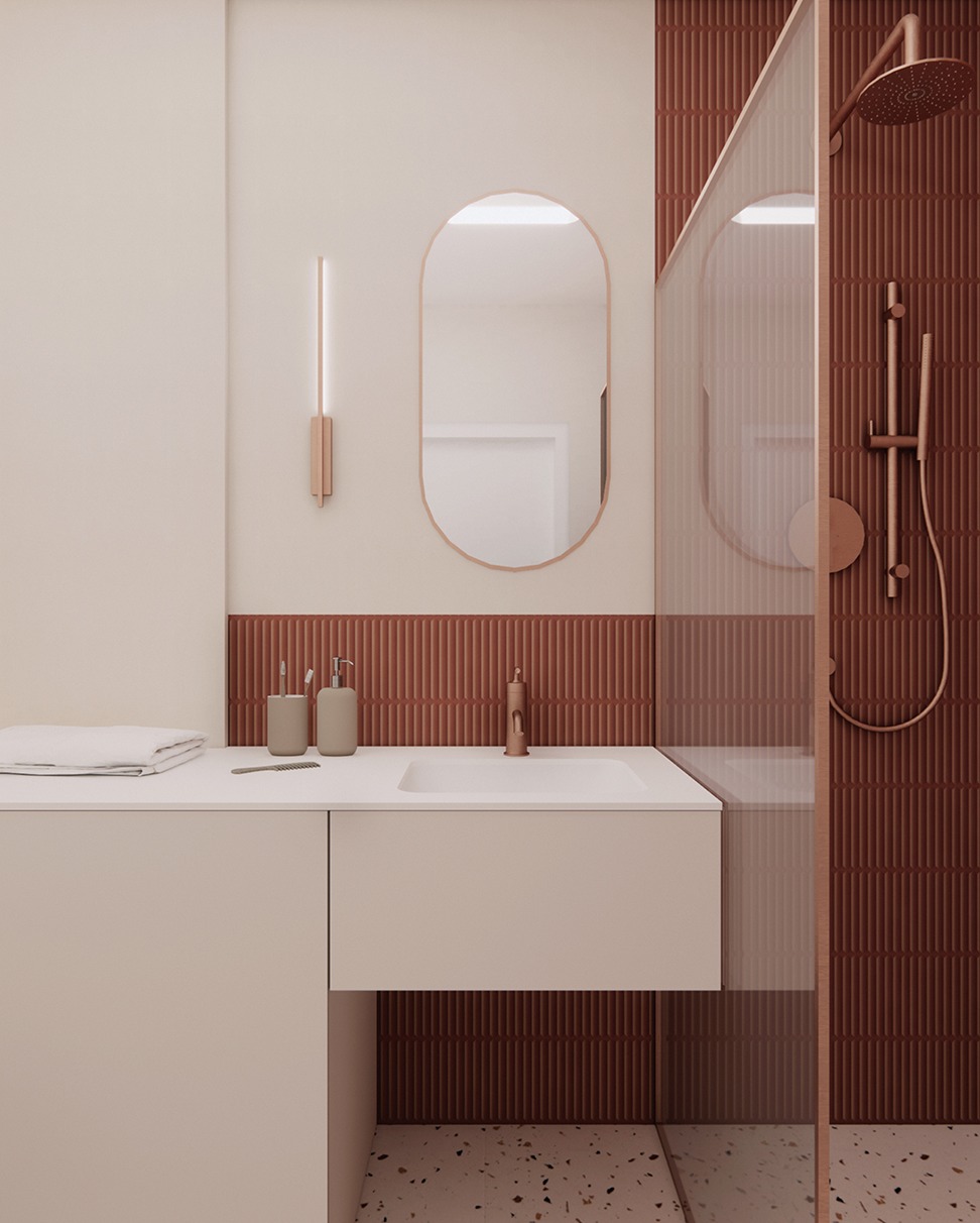 Minimalistyczna łazienka w odcieniach beżu i terakoty. Umywalka nablatowa, lustro w owalnej ramie, kabina prysznicowa ze szklaną ścianką i deszczownicą.