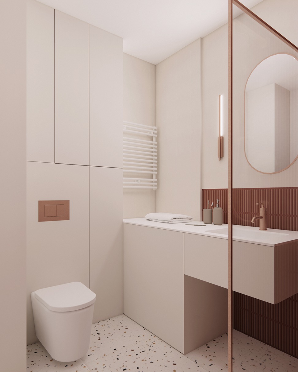 Nowoczesna łazienka w beżach z akcentami miedzianymi: toaleta podtynkowa, umywalka nablatowa, grzejnik drabinkowy, lustro owalne i mozaika na ścianie.