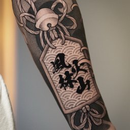 Amber Tattoo Wrocław - Ramię z unikalnym tatuażem w stylu japońskim, wykonanym we Wrocławiu. Czarno-biały wzór z motywem fal i znaków, precyzyjne cieniowanie, widoczny efekt końcowy.