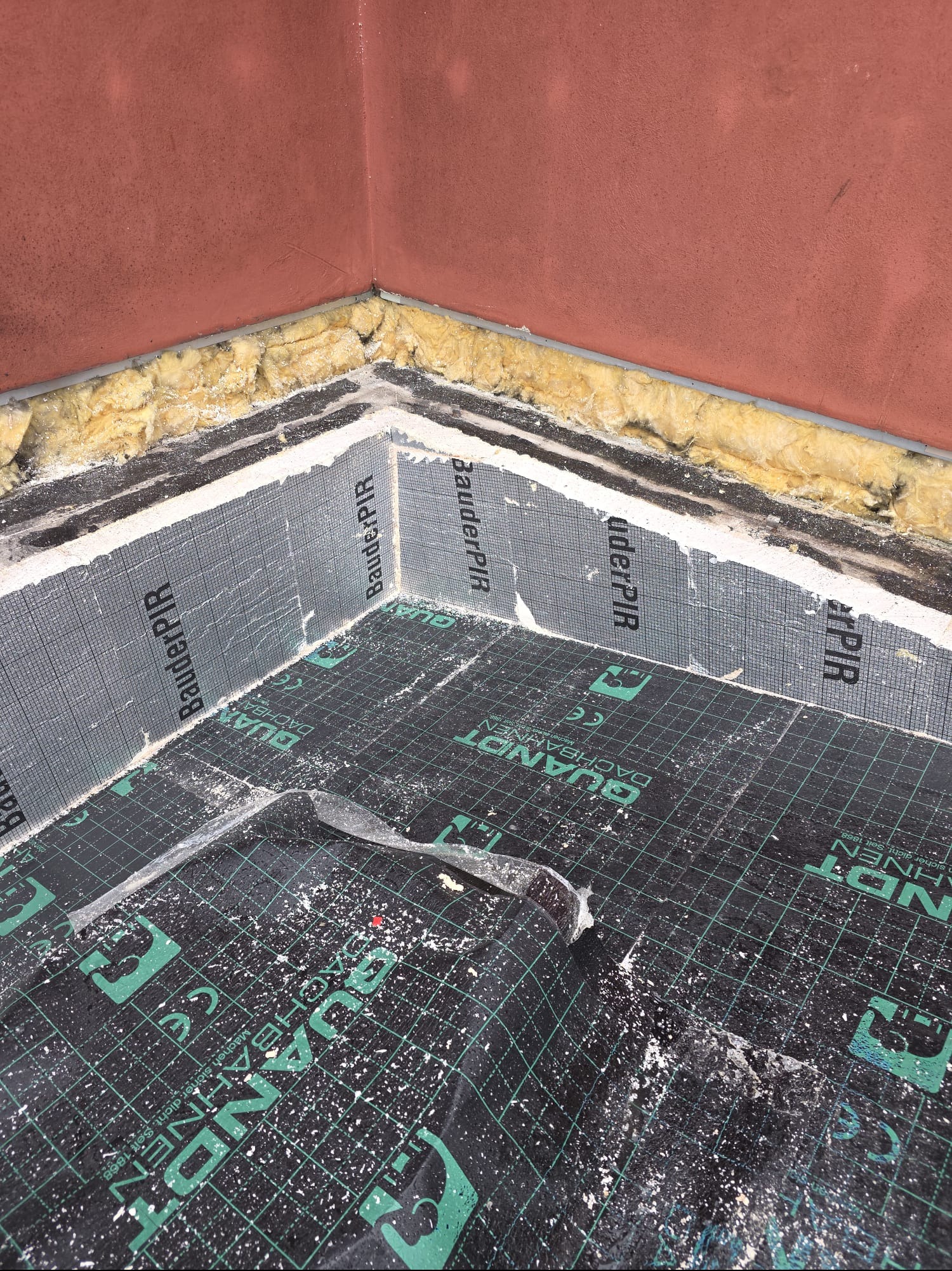 Ocieplenie poddasza z użyciem wełny mineralnej i folii paroizolacyjnej BauderPIR, widoczne detale montażu w narożniku.