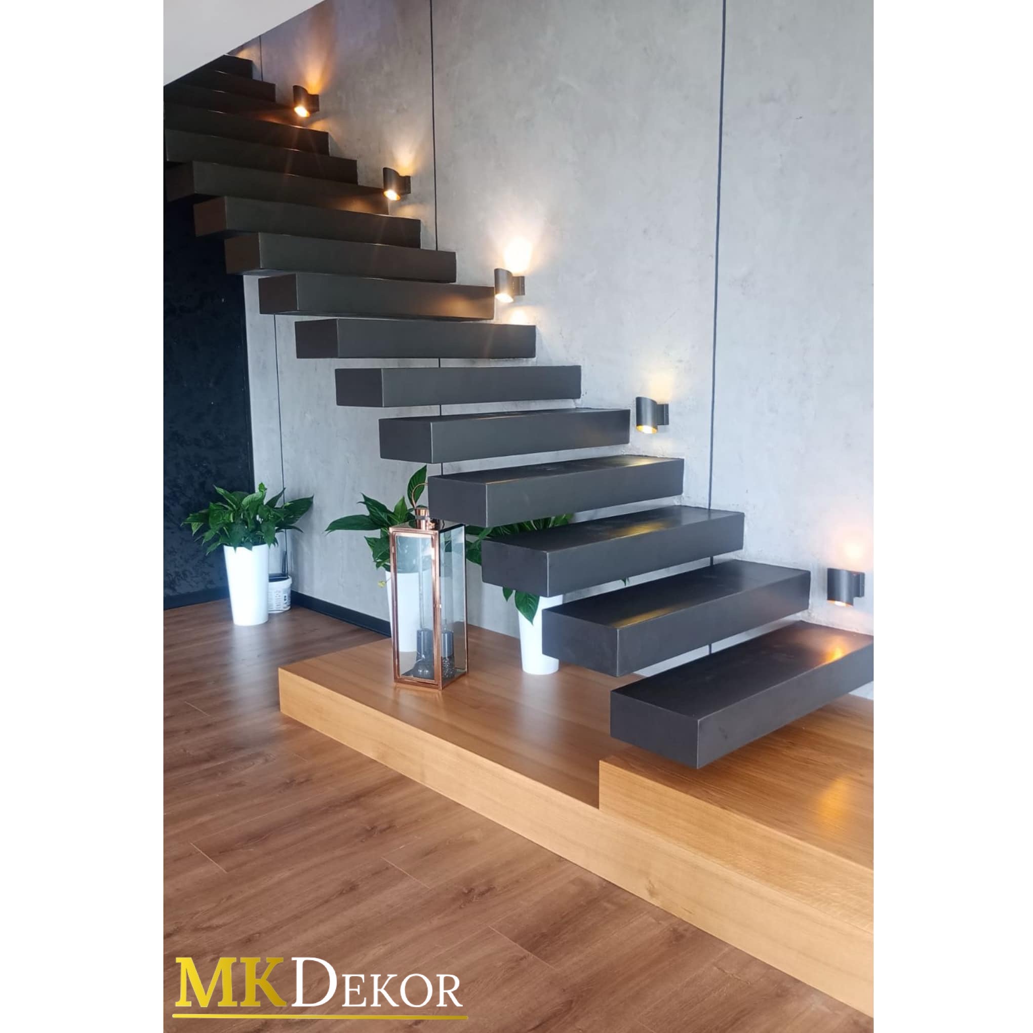 Nowoczesne schody wiszące z podświetleniem, wykończone w szarości, z drewnianą podstawą i parkietem. Minimalistyczny design z roślinami doniczkowymi.