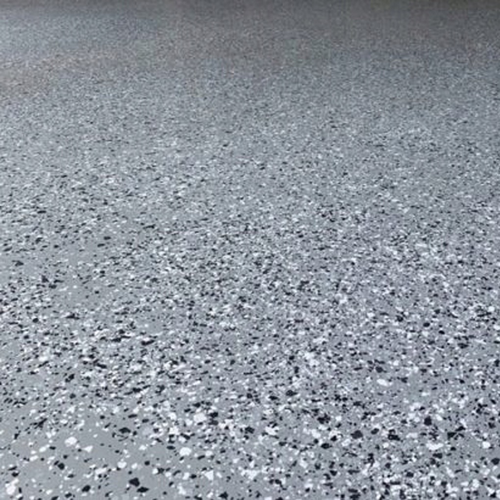 Szara posadzka żywiczna z czarnymi i białymi drobinkami, równomiernie rozłożonymi na powierzchni. Gładka, jednolita struktura, widok z perspektywy podłogi.