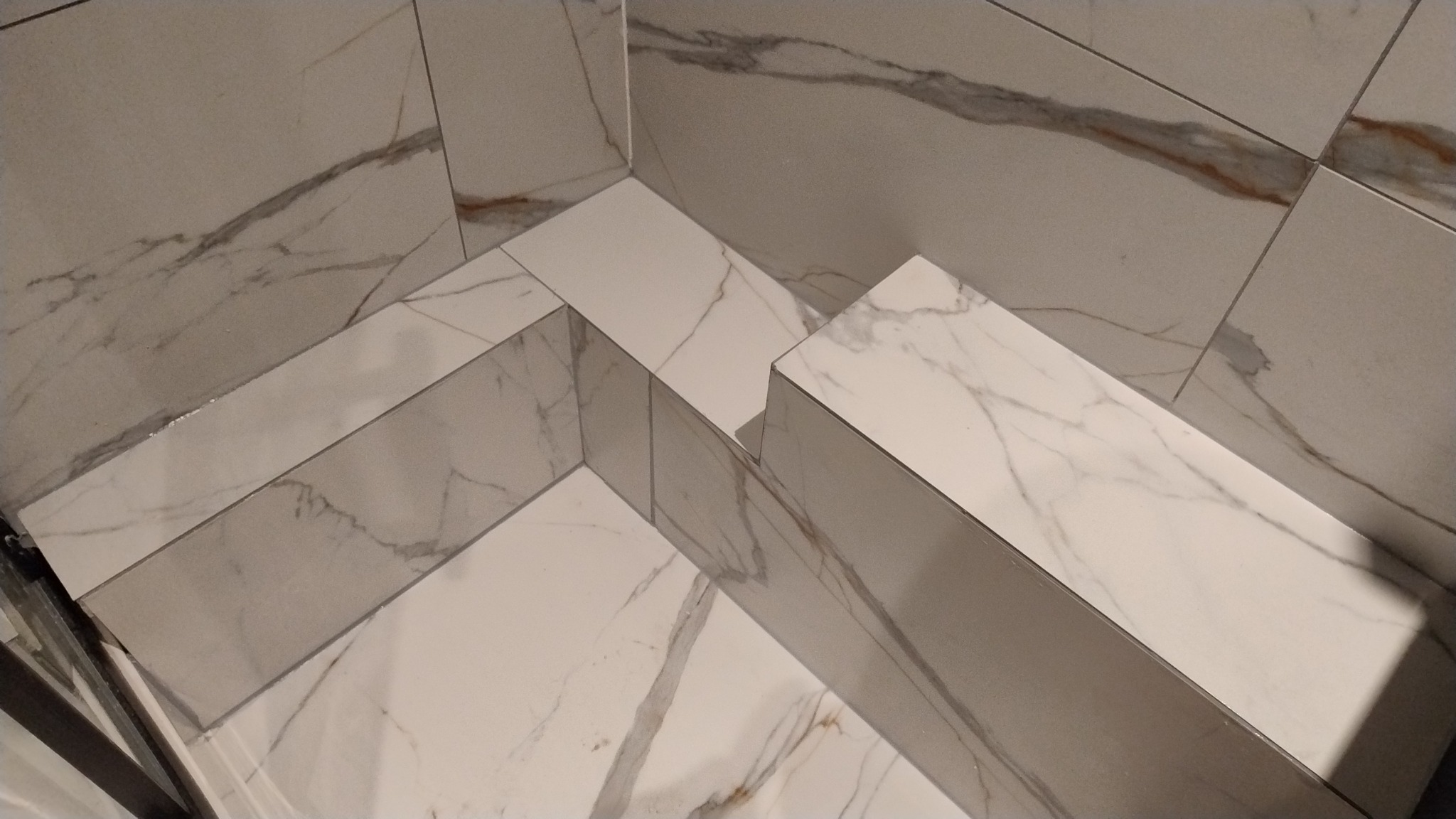 Ukończona zabudowa wnęki z płytek imitujących marmur, z widocznymi fugami i detalami wzoru. Estetyczne wykończenie narożników.