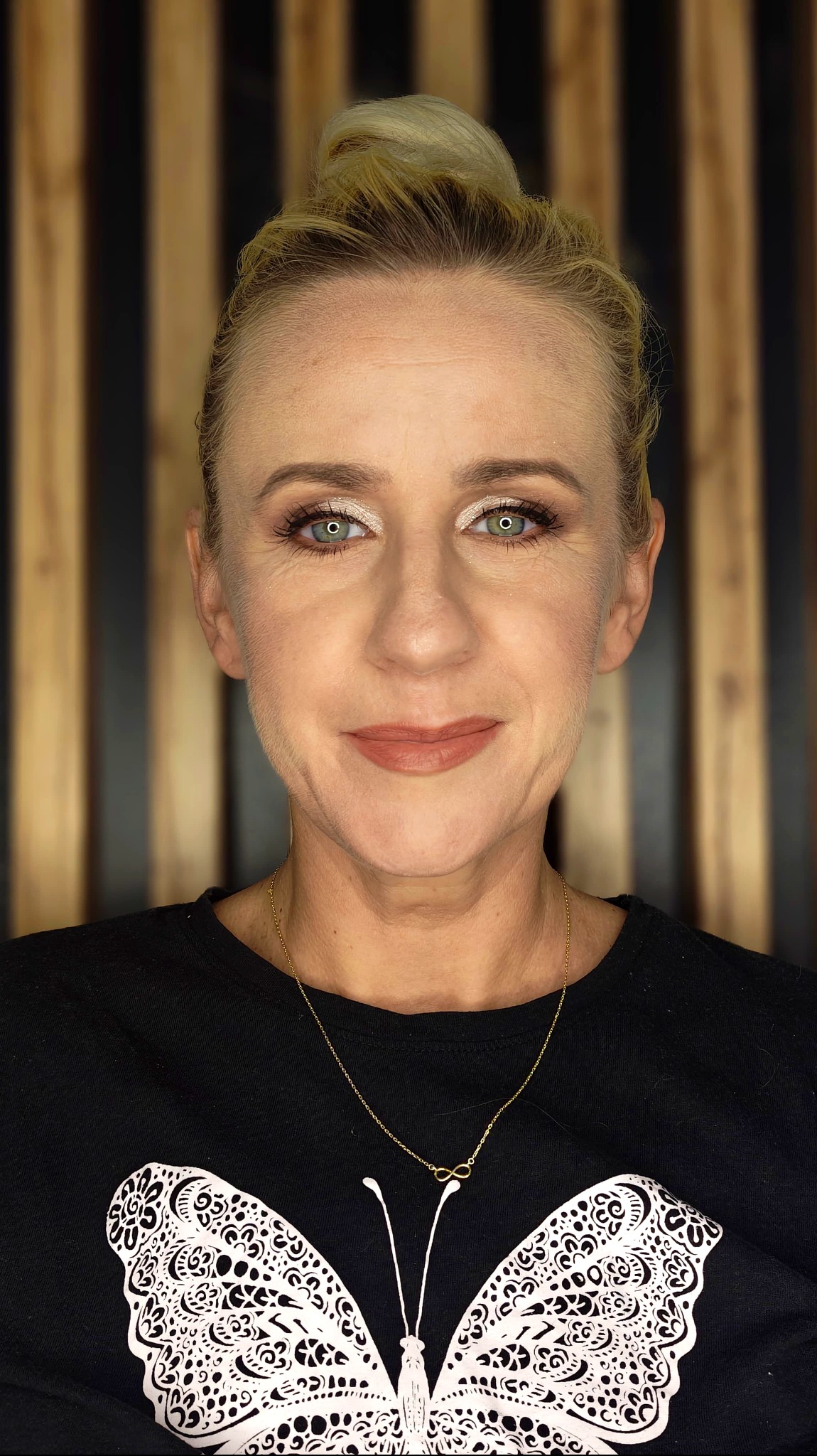 Portret kobiety z delikatnym, rozświetlającym make-upem w Gdańsku. Widoczne podkreślone oczy i usta w odcieniu nude. Tło stanowią pionowe panele.