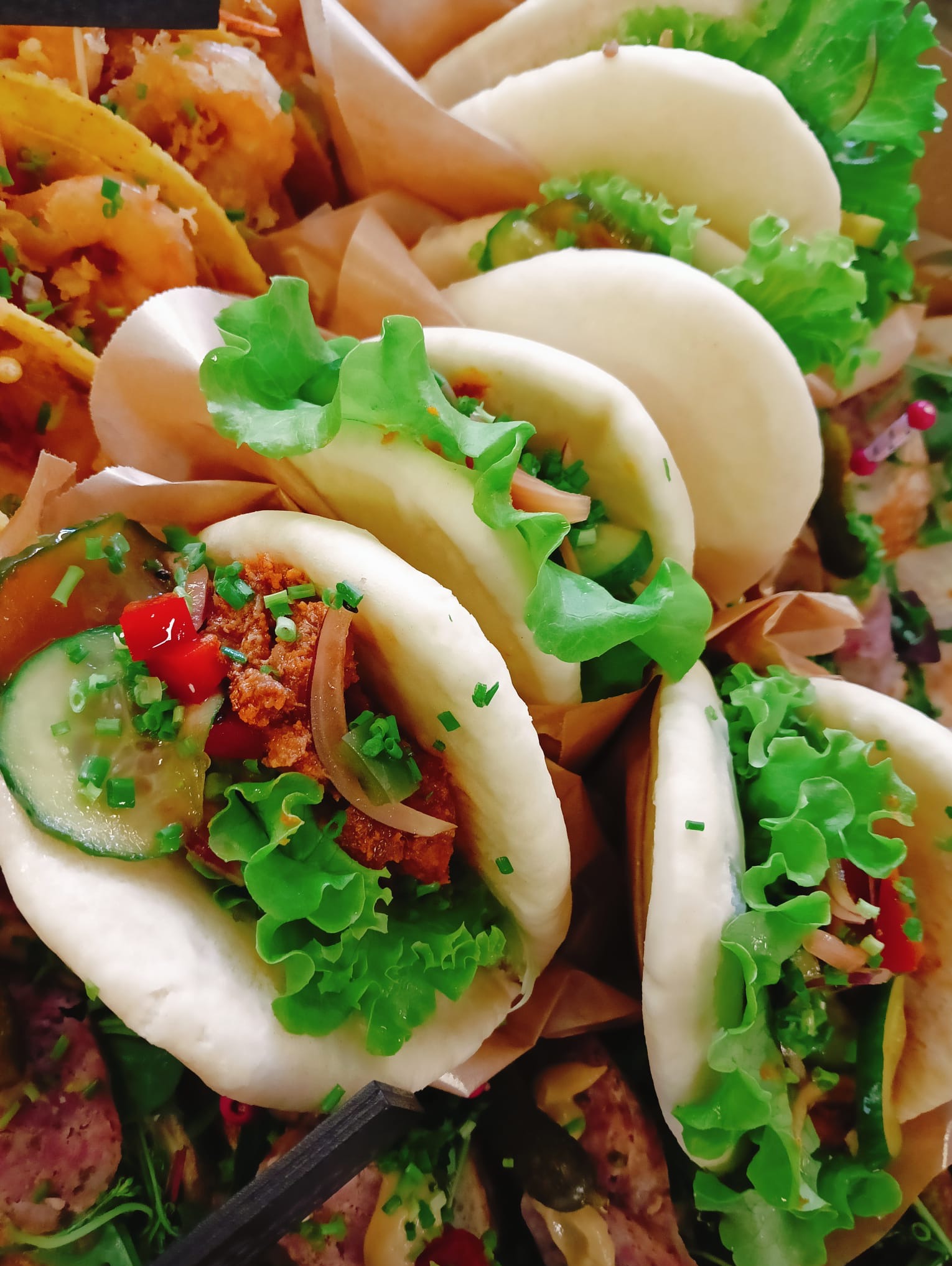 Aromatyczne bao buns z warzywami i mięsem, ułożone na papierze, gotowe do serwowania. Widoczne świeże składniki i dbałość o estetykę podania.