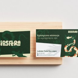 cwiertka.pl Kamil Ćwiertka - Dwie wizytówki firmy Biosfera na drewnianym tle. Jedna z logo i grafiką, druga z danymi kontaktowymi i hasłem: Egzotyczna edukacja na wyciągnięcie ręki.