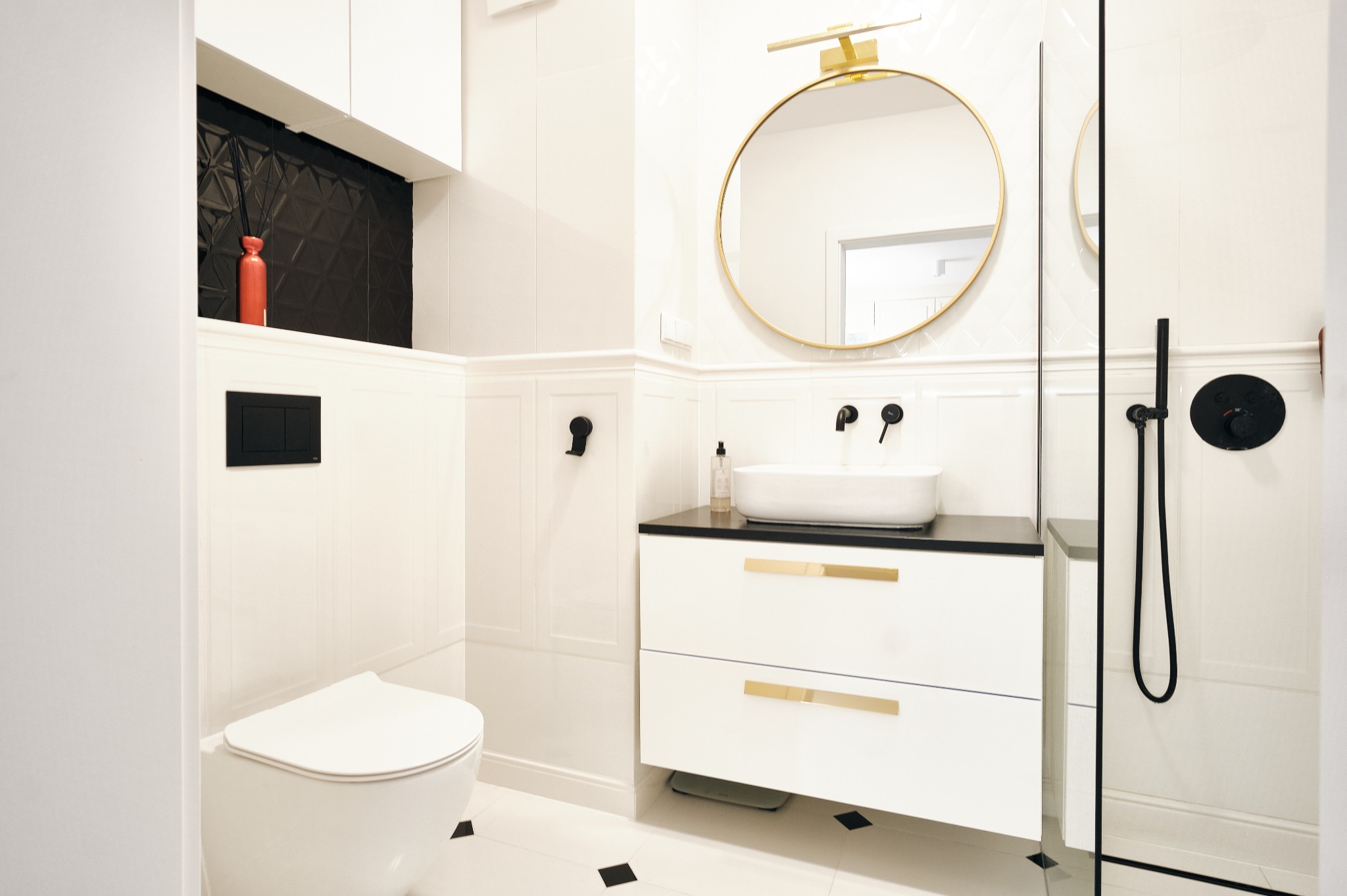 Elegancka łazienka w Łapalicach z białymi płytkami, czarnymi akcentami i okrągłym lustrem. Nowoczesny design z umywalką nablatową i kabiną prysznicową.
