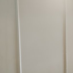 Usługi budowlane - Biała ściana z dekoracyjną ramką, świeżo po malowaniu. Minimalistyczny design, gładka powierzchnia, subtelne oświetlenie podkreśla detale wykończenia.