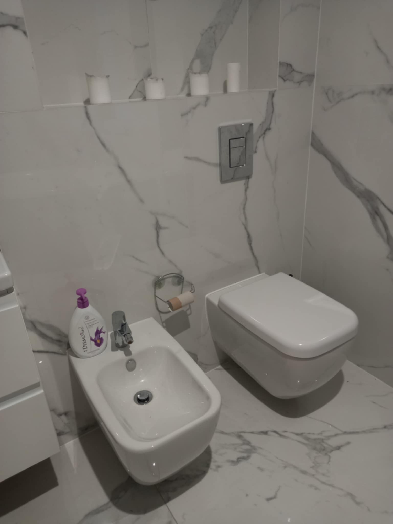 Biała armatura łazienkowa (bidet i toaleta) na tle marmurowych płytek w Siedlcach. Minimalistyczny design, czystość i elegancja w wykończeniu wnętrza.