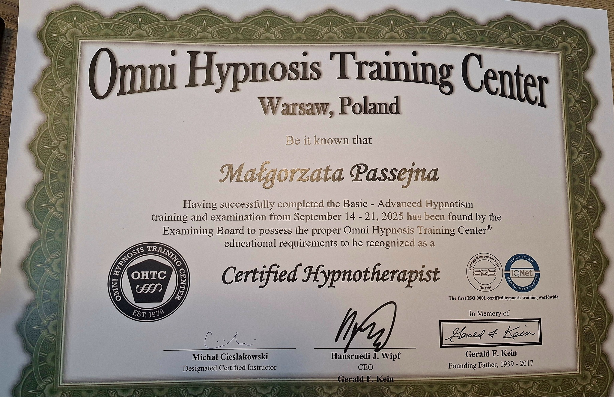 Certyfikat ukończenia kursu hipnoterapii w Omni Hypnosis Training Center w Warszawie, imienny, z podpisami instruktorów i pieczęciami. Dokument w ramce.