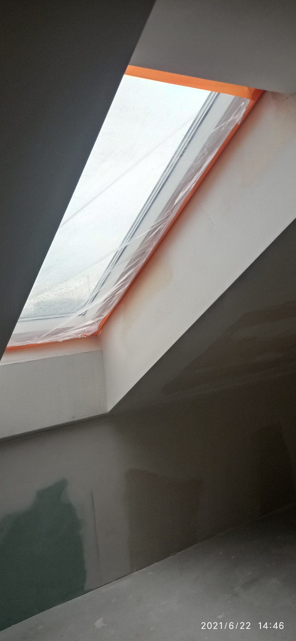 Szpachlowanie ścian i sufitu w Szczecinie, przygotowanie do malowania. Okno dachowe zabezpieczone folią. Ściany gładkie, gotowe do dalszych prac wykończeniowych.