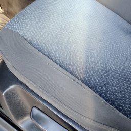 Usługi czyszczące Ziela - Szczegółowe ujęcie fotela samochodowego z szarą tapicerką o delikatnym wzorze, widoczny mechanizm regulacji. Czyste, zadbane wnętrze pojazdu.