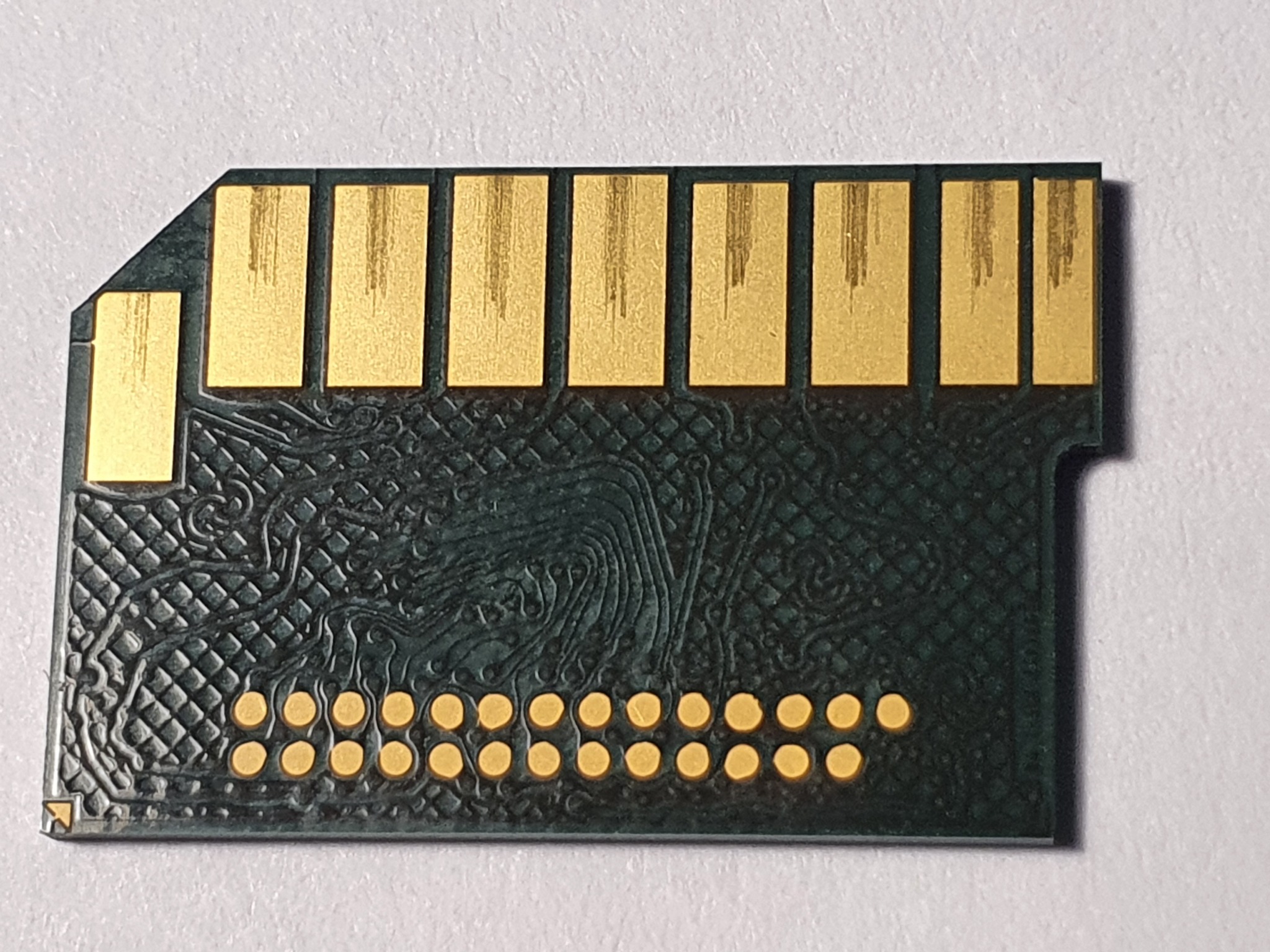 Zbliżenie na kartę pamięci SD z widocznymi złotymi stykami i zielonym obwodem. Detaliczna faktura i precyzyjne wykonanie. Makro detale elektroniki.