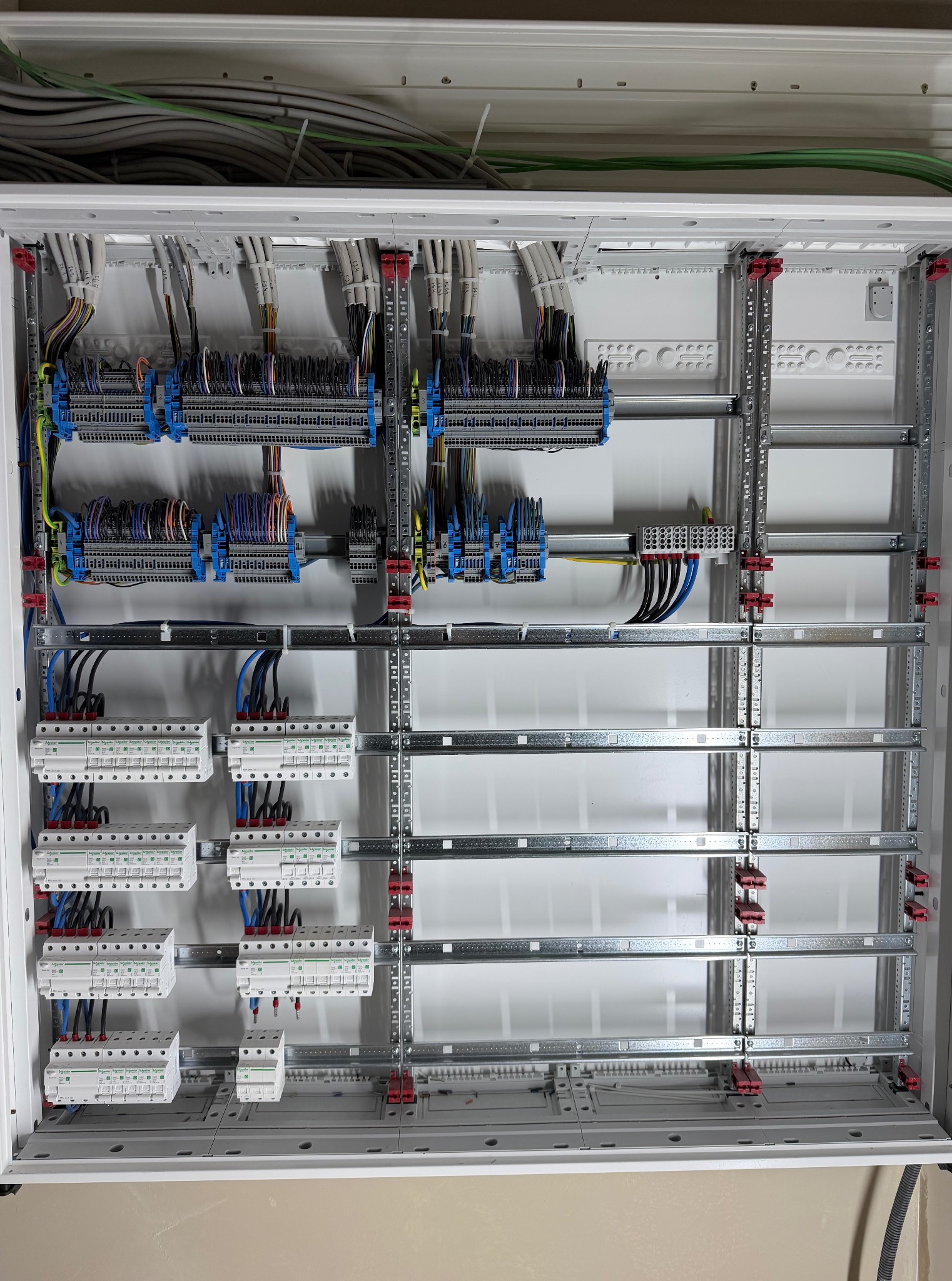 Rozdzielnica elektryczna w trakcie montażu: widoczne szyny DIN, listwy zaciskowe, przewody i zabezpieczenia. Estetyczne ułożenie kabli wewnątrz skrzynki.