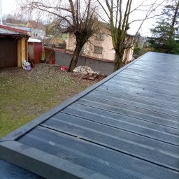 Jagiellońska 111 - Szary taras kompozytowy z widokiem na podwórze z drzewami i budynkami w tle, uchwycony z góry pod kątem. Deski ułożone poziomo, widoczne mocowania.