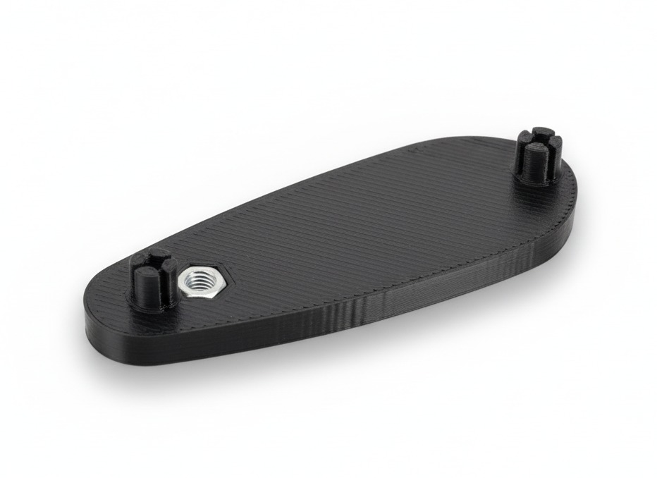 Czarny, wydrukowany w 3D element z tworzywa sztucznego z wtopionymi nakrętkami, leżący na białym tle. Widoczne charakterystyczne warstwy druku.