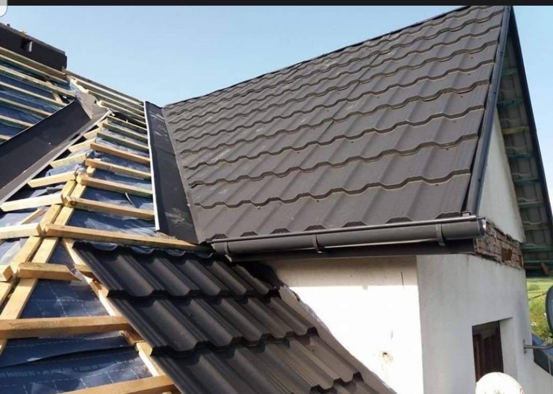 Częściowo pokryty dach z blachodachówki w Łodzi. Widoczne elementy konstrukcji dachu i rynna. Nowe pokrycie w kolorze grafitowym.