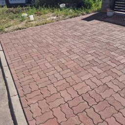 Clean-Mar Wiesław Śliwa - Czerwona kostka brukowa ułożona na podjeździe, widoczny fragment samochodu z napisem 'Mycie ciśnieniowe', narzędzia i wiadro. Słoneczny dzień.