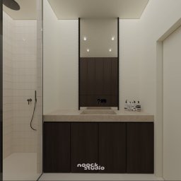 noock.studio - Minimalistyczna łazienka z kabiną prysznicową, umywalką z szafką i lustrem w ciemnej ramie. Beżowe płytki i stonowana kolorystyka tworzą spójną całość.