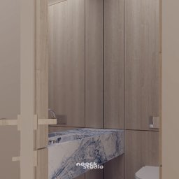 noock.studio - Nowoczesna łazienka z marmurową umywalką i drewnianymi szafkami. Minimalistyczny design, stonowana kolorystyka, widoczne logo 'noock.studio' na umywalce.