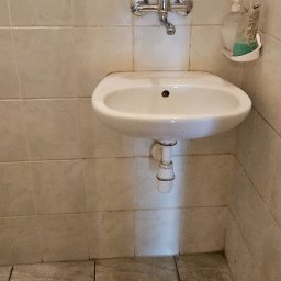 MAXI-ZIM DAMIAN KUCHARSKI - Umywalka z lustrem i półką w łazience, widoczne ślady użytkowania. Usługi porządkowe w Dębnie.