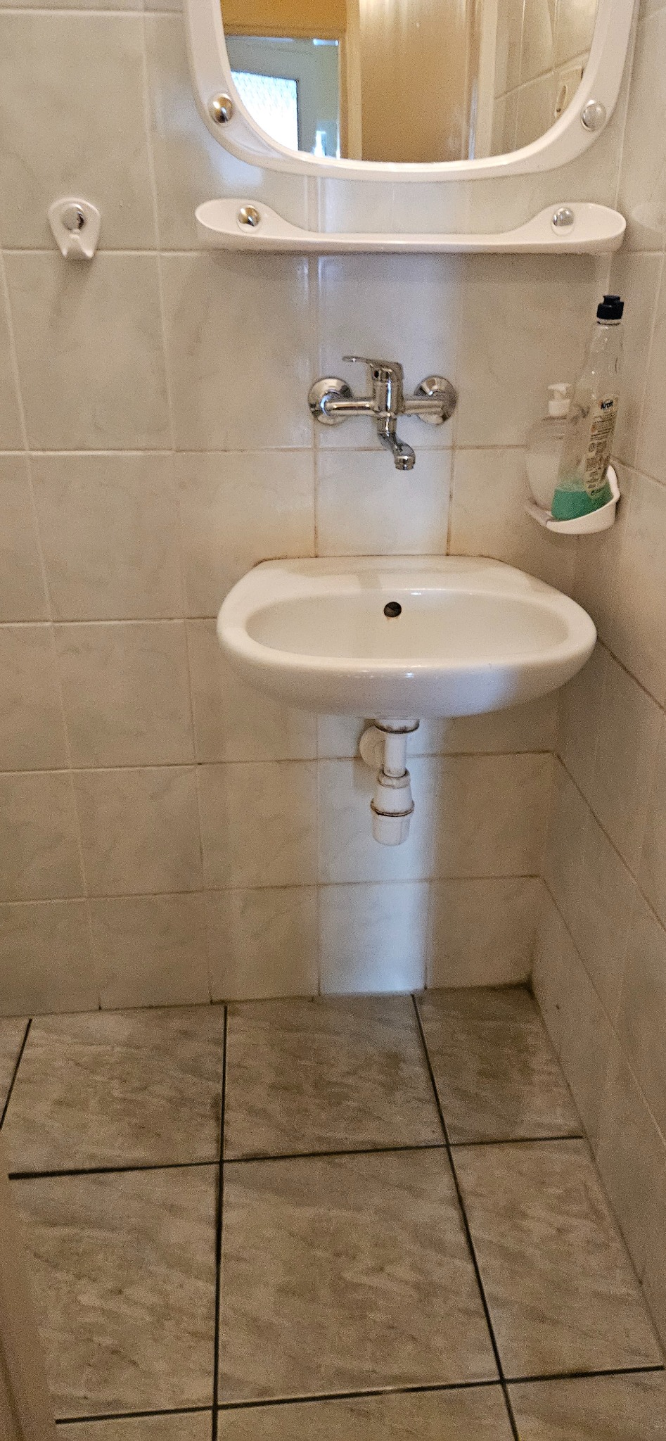 Umywalka z lustrem i półką w łazience, widoczne ślady użytkowania. Usługi porządkowe w Dębnie.