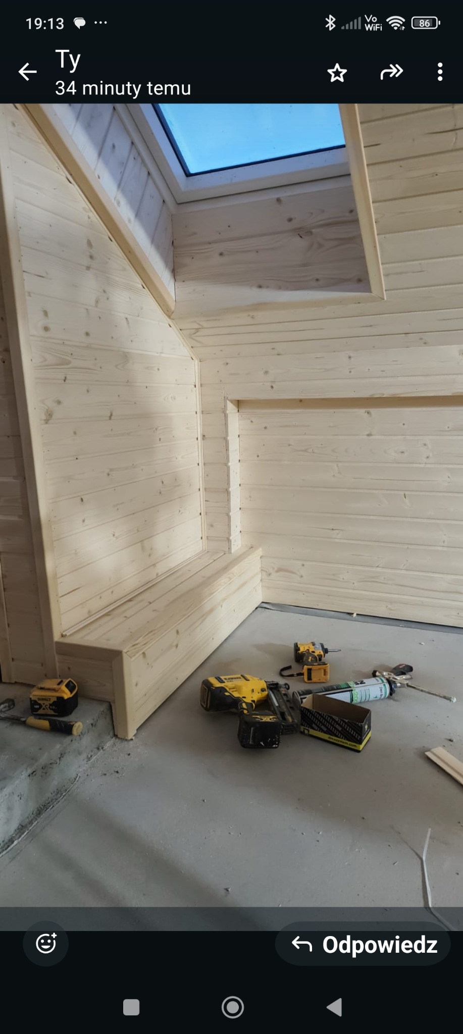 Drewniana boazeria w jasnym odcieniu, zamontowana na ścianach i suficie poddasza w Sieniawie. Widoczne narzędzia pracy na podłodze, okno dachowe.