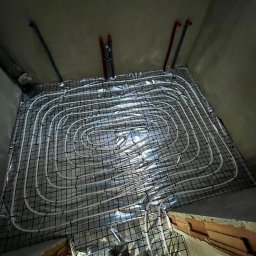 HydroPro Jakub Hereda - Białe rury ogrzewania podłogowego na folii, zamocowane do siatki, widok z góry, Rzyki. Elementy instalacji grzewczej w surowym wnętrzu.